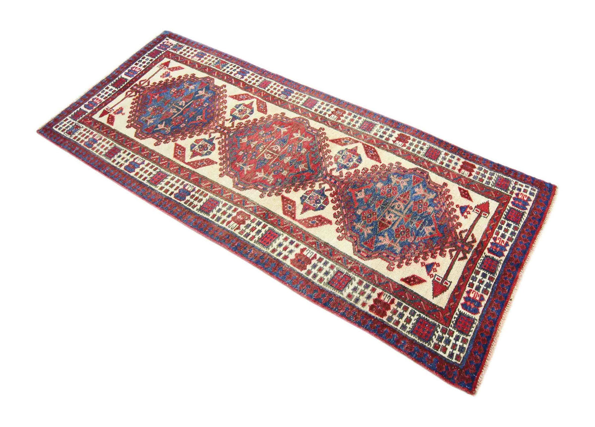 Vintage Persian Serab runner with red and blue geometric medallions on a cream wool field and patterned border.