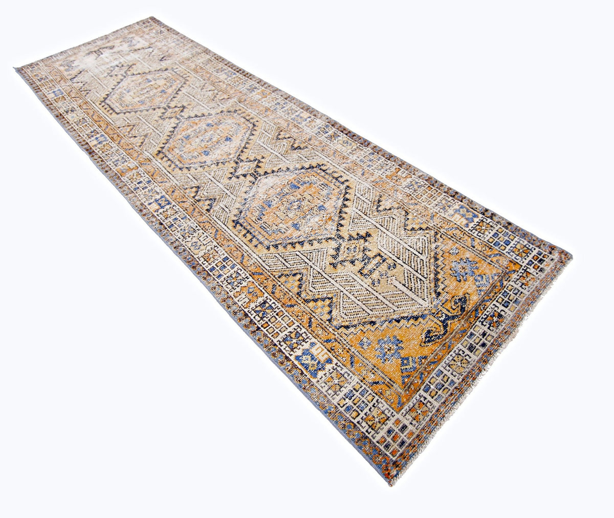 Vintage Persian Serab runner featuring geometric medallions in muted gold, blue, and cream wool with a fringed edge.