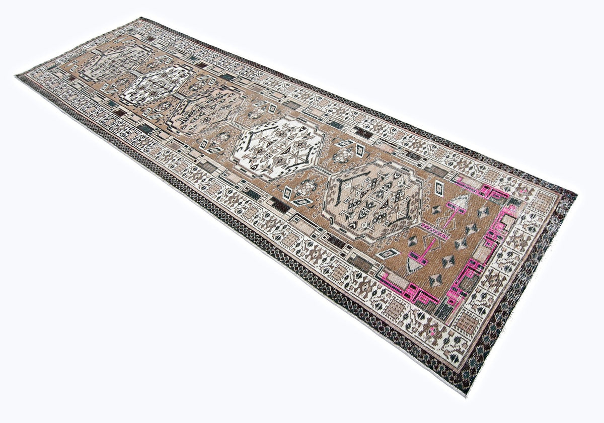 Vintage Persian Serab runner featuring geometric medallions in earthy brown, cream, and vibrant pink wool.