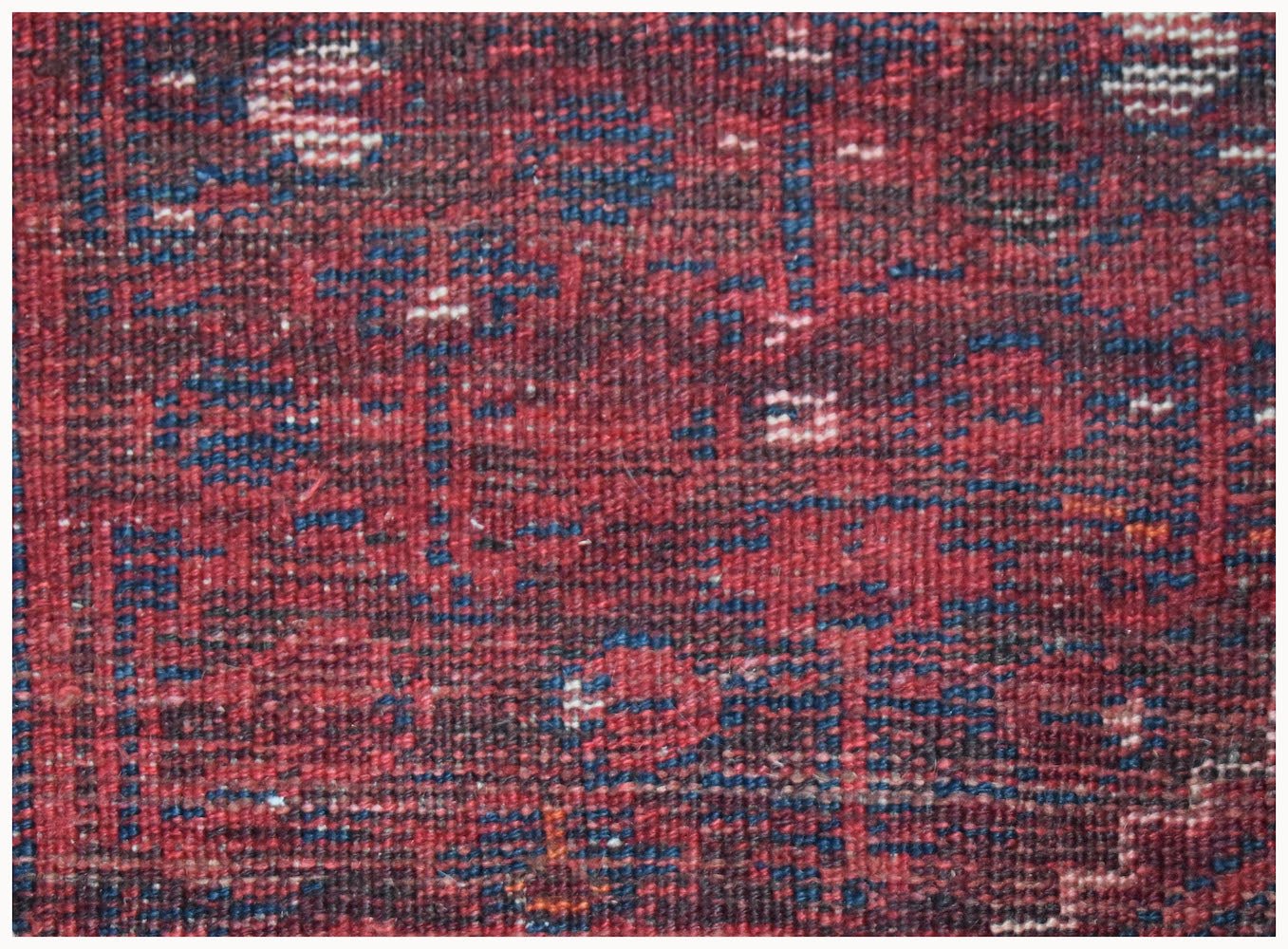 A close-up view of a handwoven vintage Persian Shiraz rug featuring a deep red and blue pattern.