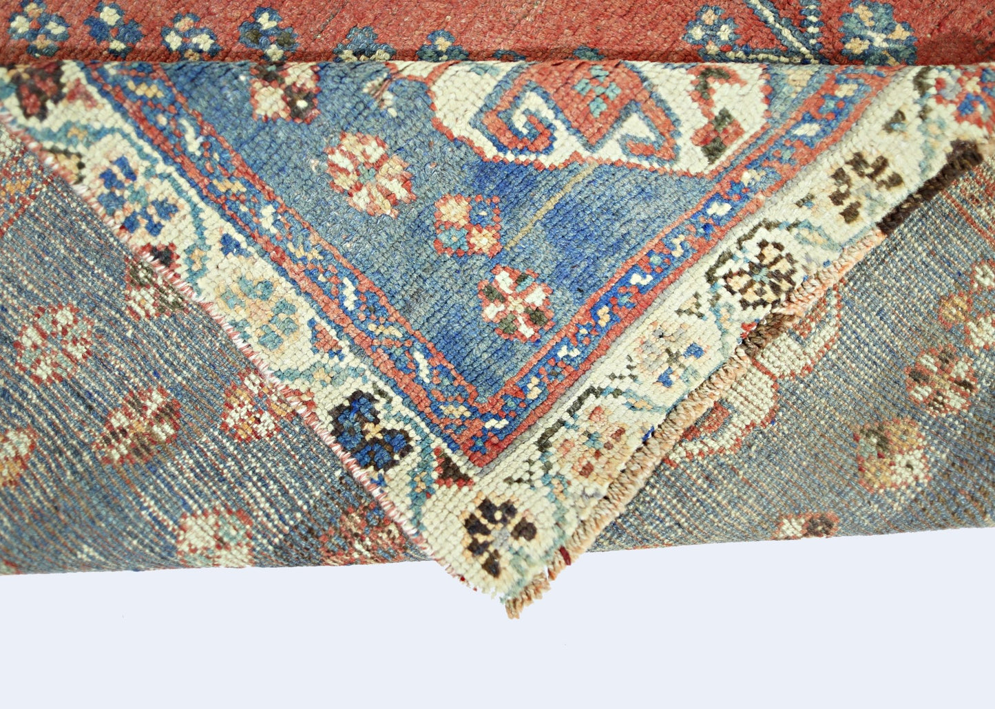 A folded vintage Persian Shiraz rug featuring intricate blue and red geometric floral patterns.