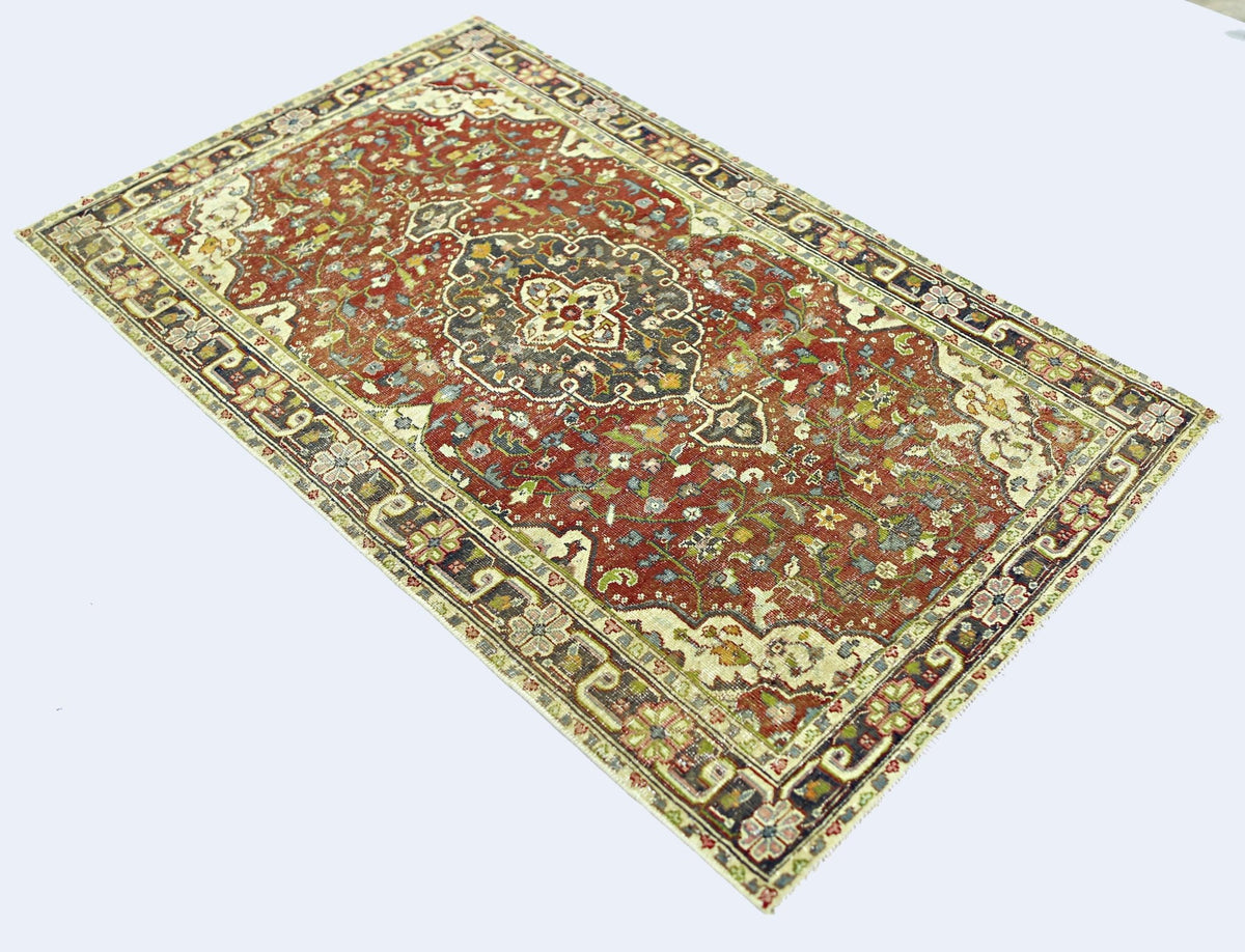 A rectangular vintage Persian rug featuring a central medallion on a red field with floral patterns.