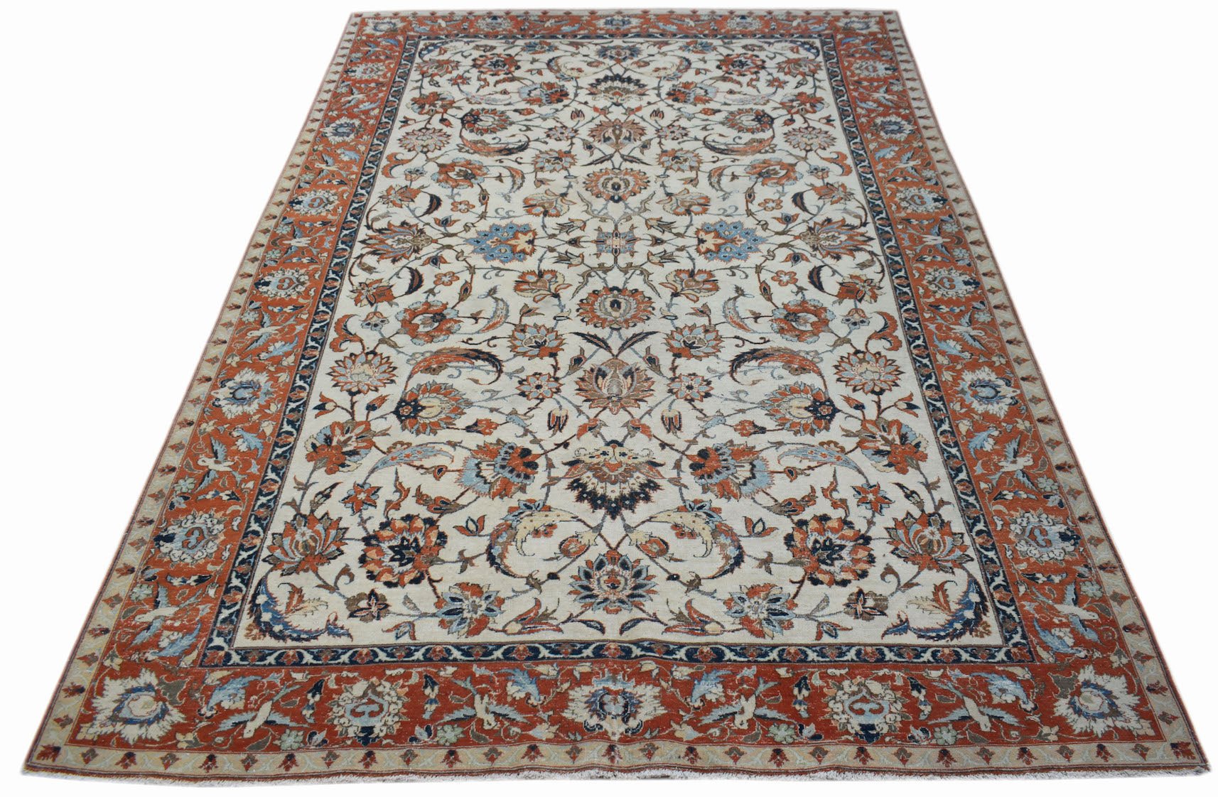 A vintage Persian Kashan rug featuring intricate floral patterns in rust, blue, and cream tones.