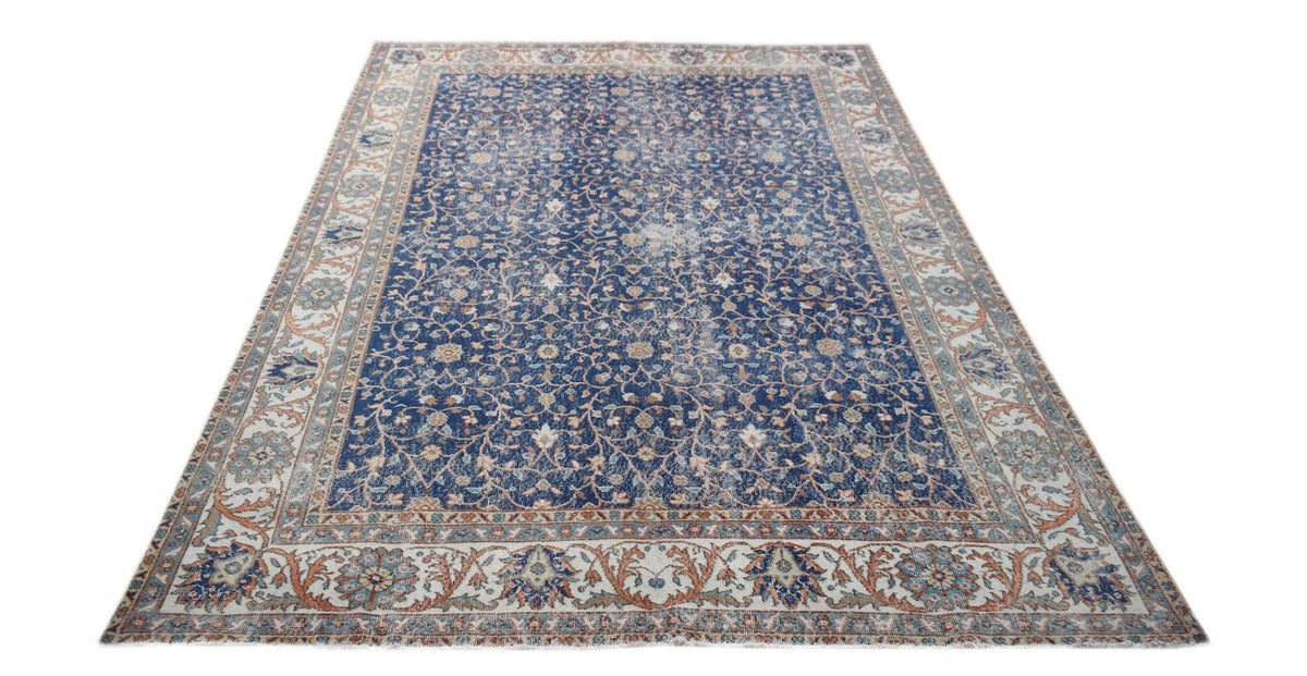 A vintage Persian Tabriz rug featuring a blue field with intricate floral patterns and a wide border.
