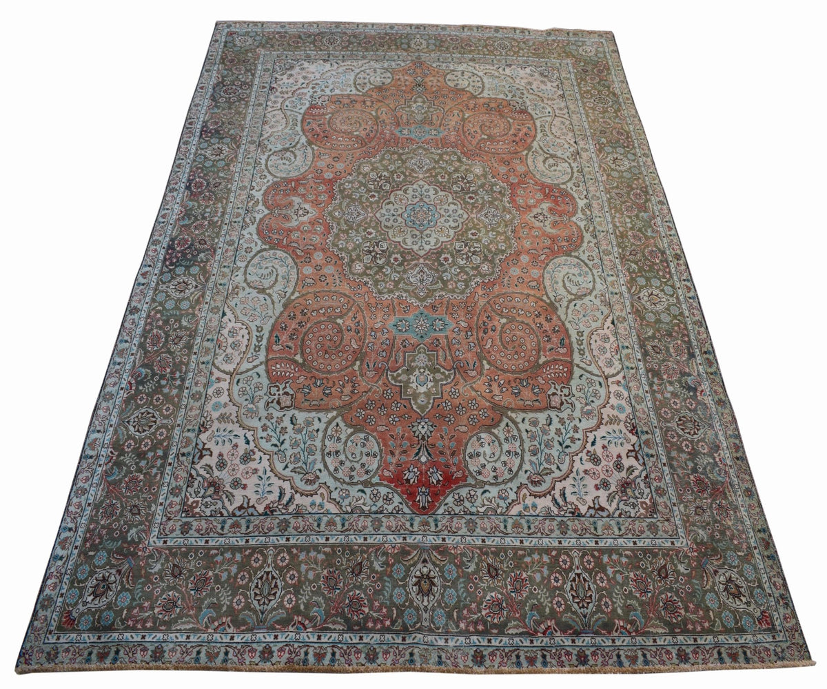 A vintage handwoven Persian Tabriz rug featuring intricate floral patterns in orange and green.