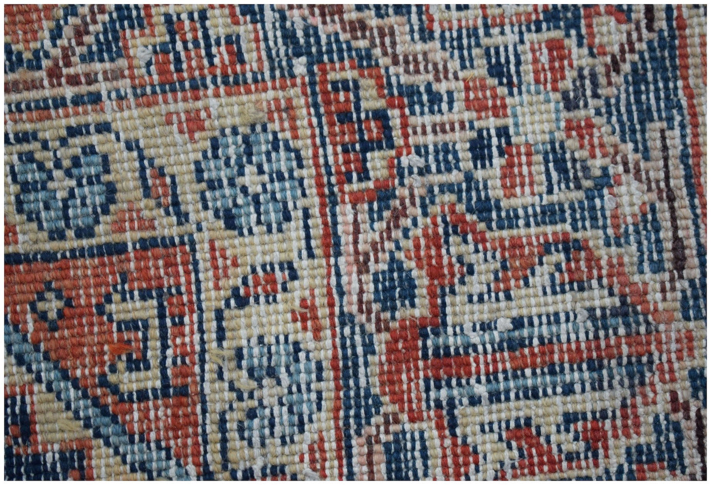 A close-up view of a handwoven vintage Persian rug featuring intricate geometric patterns in wool.