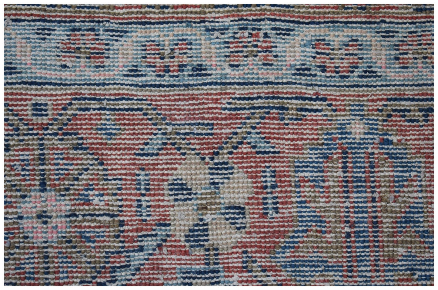 A close-up view of a vintage Persian rug featuring intricate floral patterns in red, blue, and tan.