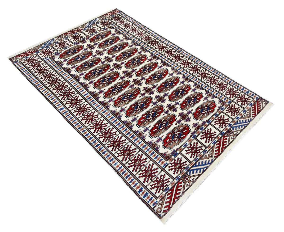 Hand-knotted Pakistani Princess Bokhara rug with red and blue gul patterns on a cream wool field and fringed edges.