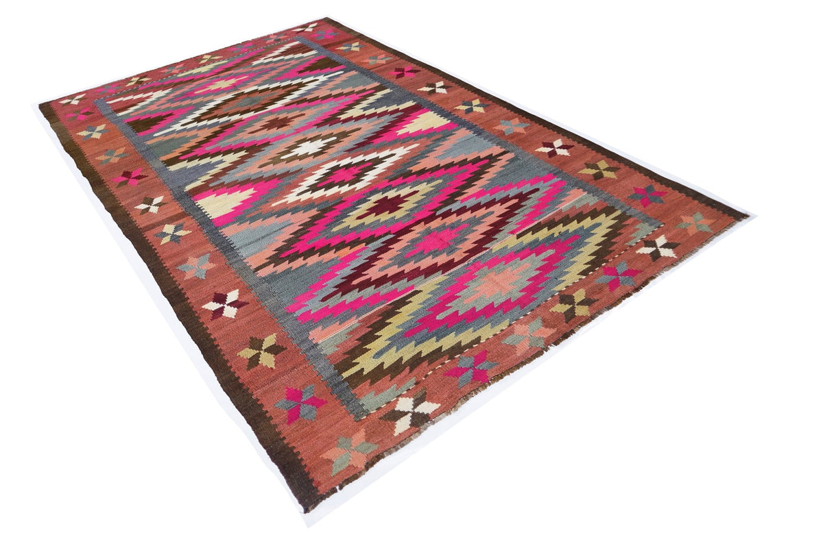 Vintage Anatolian kilim featuring a geometric diamond pattern in vibrant pink, grey, and earthy red tones.