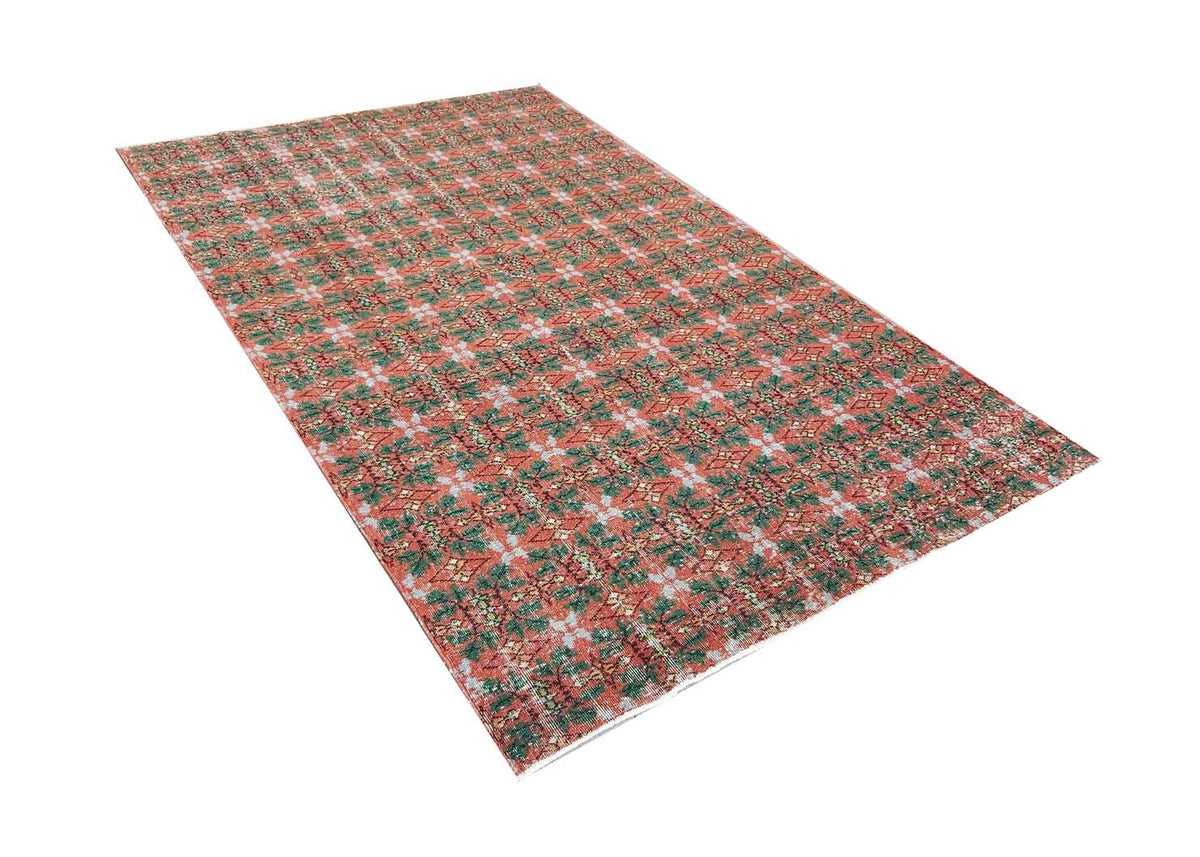 A vintage handmade Turkish wool rug featuring a repeating geometric pattern in red and green.