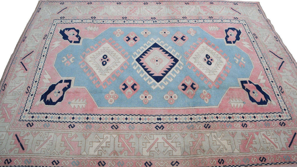 Vintage Turkish Oushak rug featuring a geometric pattern in shades of blue, pink, and cream.