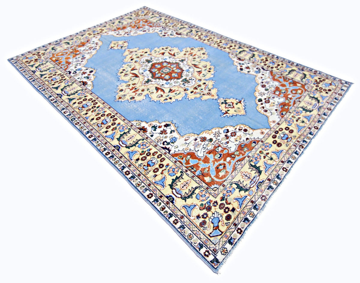Vintage Anatolian rug with a central medallion, featuring blue, cream, and rust-red floral patterns on a white background.