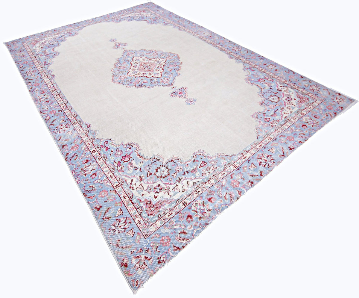 Vintage Turkish Anatolian rug with a pale cream field, central medallion, and intricate blue and pink floral borders.