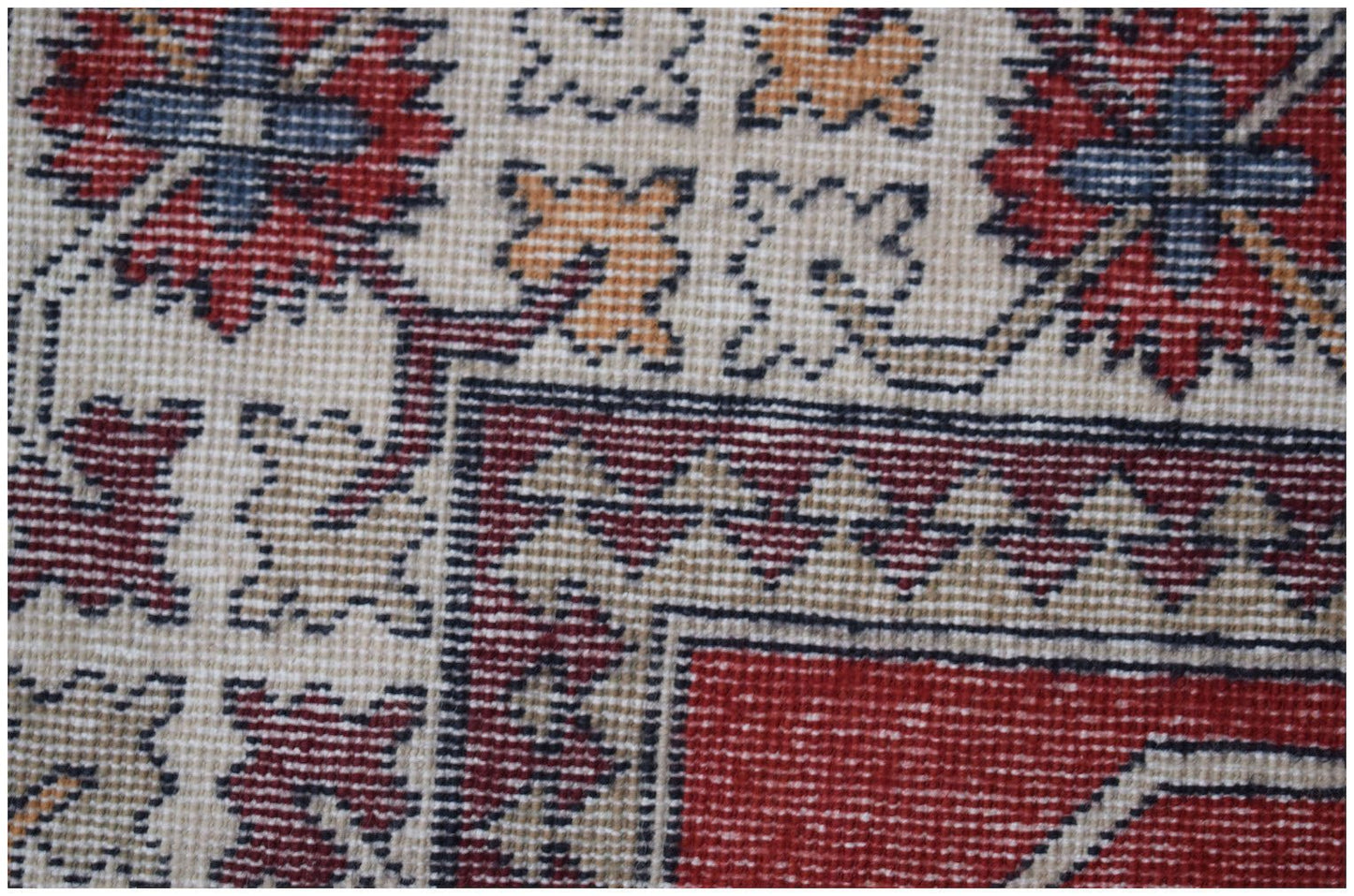A close-up of a vintage Turkish runner featuring geometric floral motifs in red, blue, and tan.