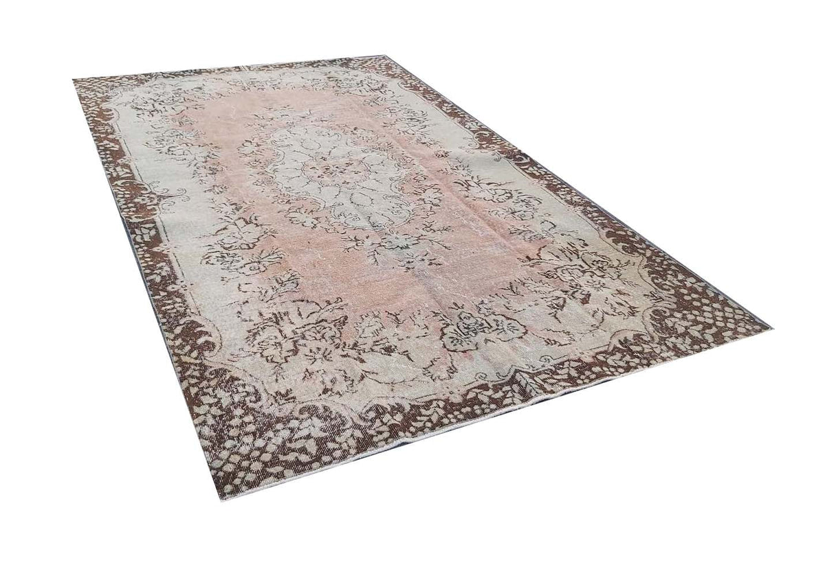 A vintage Turkish Isparta rug featuring a soft pink central floral design with a dark brown border.