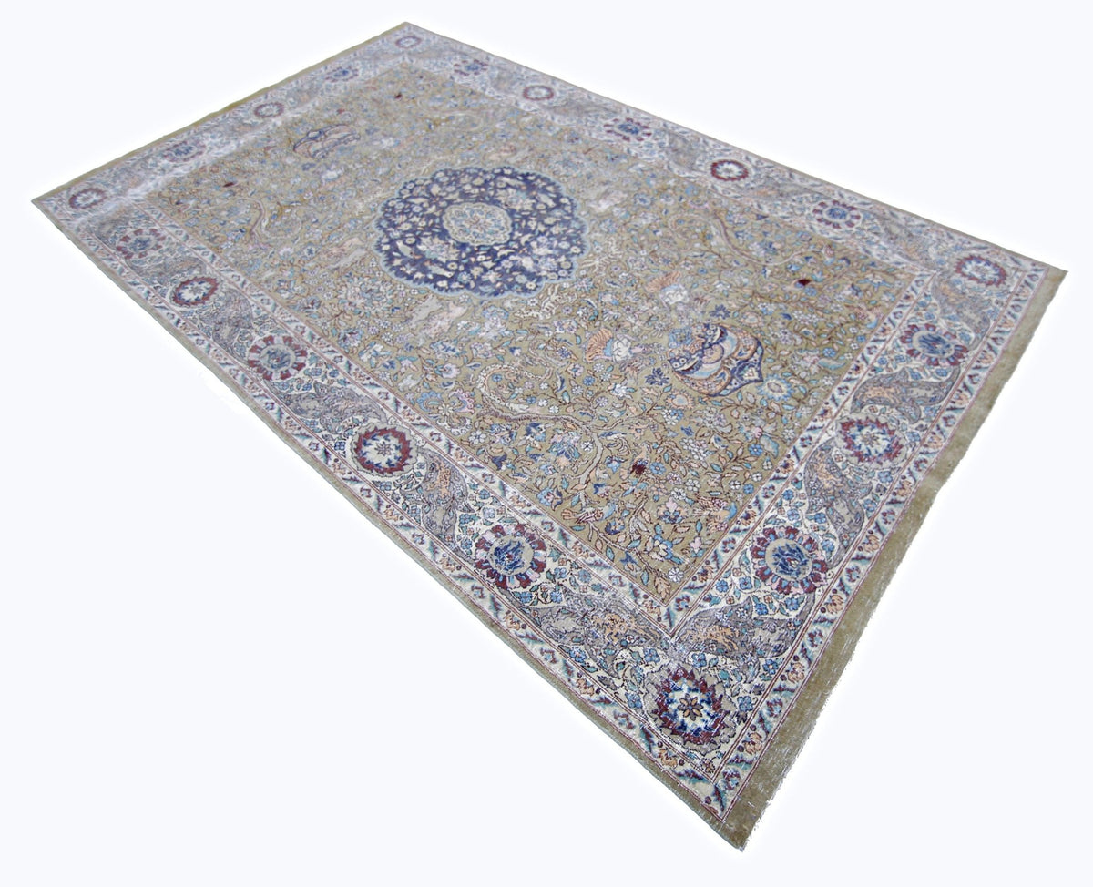Vintage Kayseri rug with a central blue floral medallion, intricate scrolling vines, and a soft olive field.
