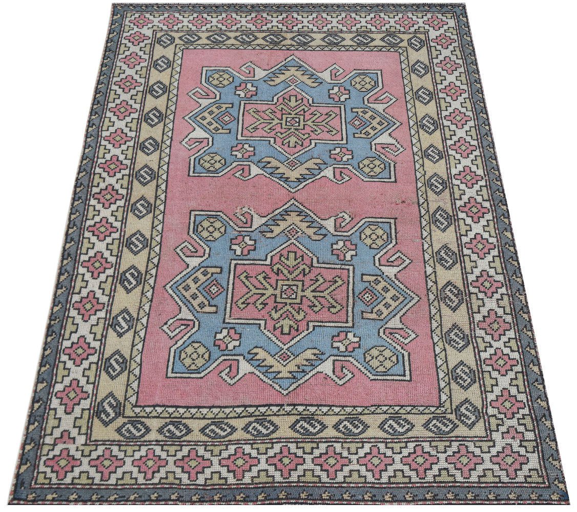Vintage Turkish Milas rug with pink, blue, and cream geometric patterns.