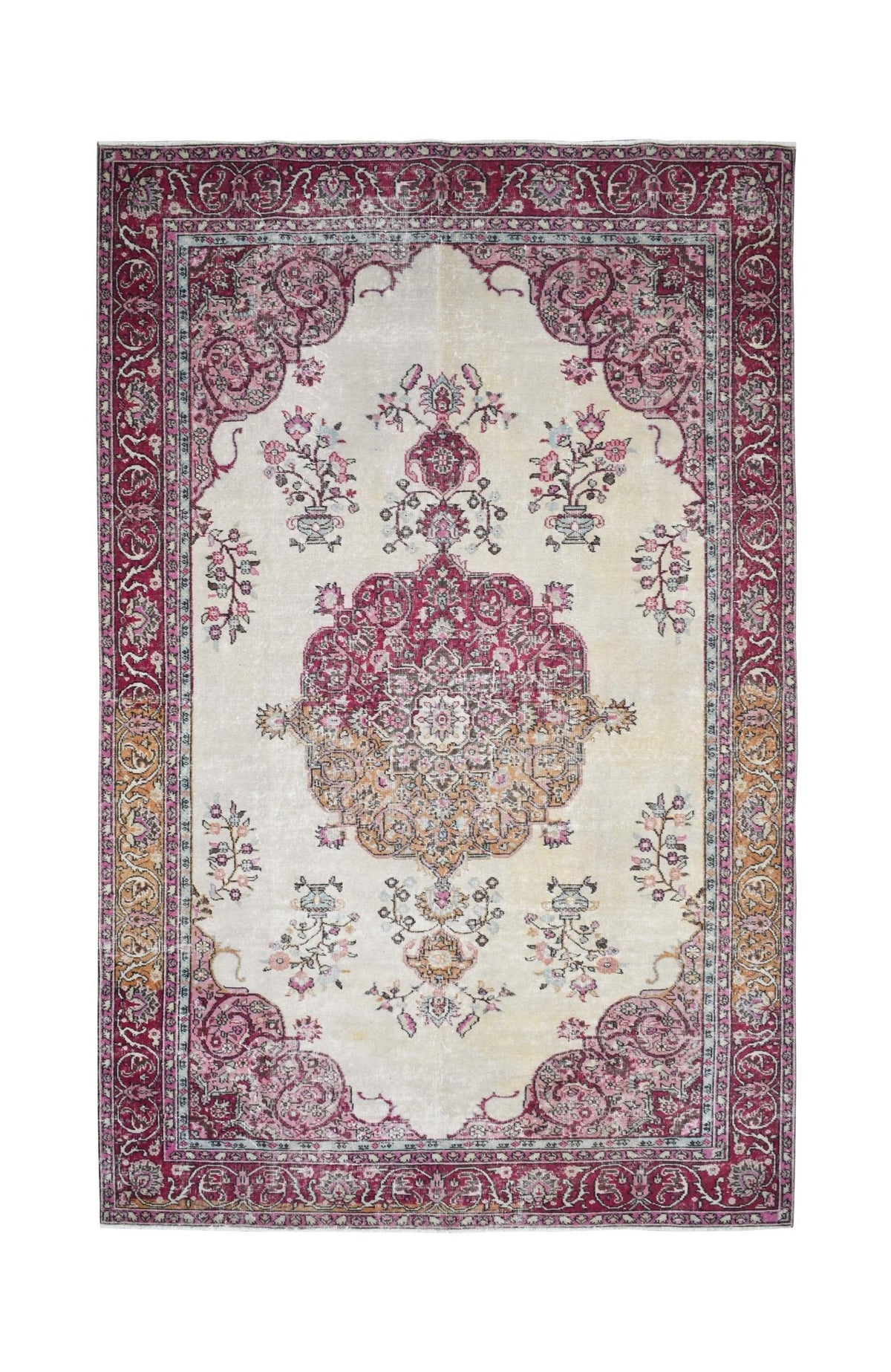 A vintage handmade Turkish rug featuring a central medallion and floral motifs in pink and cream.
