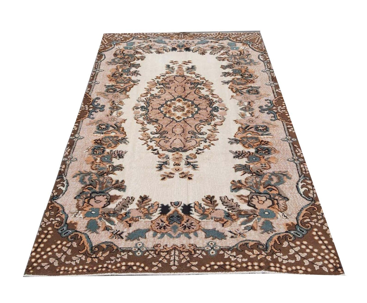 A vintage handmade Turkish Isparta rug featuring a floral medallion on a cream field.