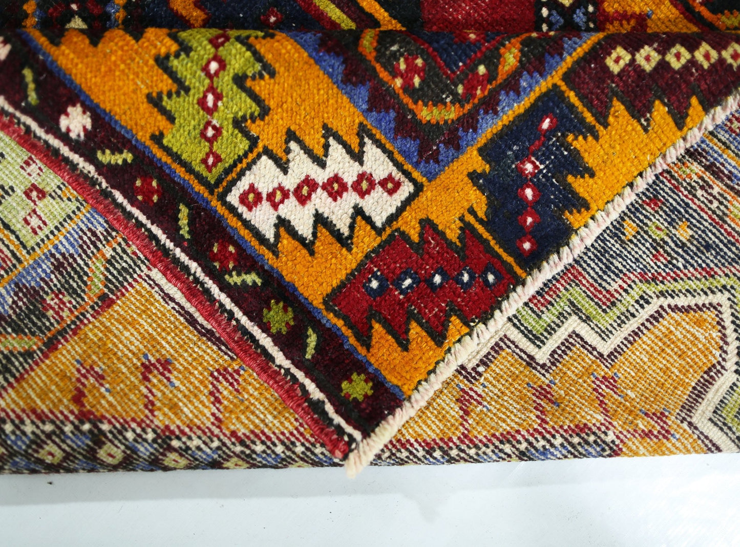 A close-up view of a vintage Turkish Taspinar rug featuring vibrant geometric patterns in wool.