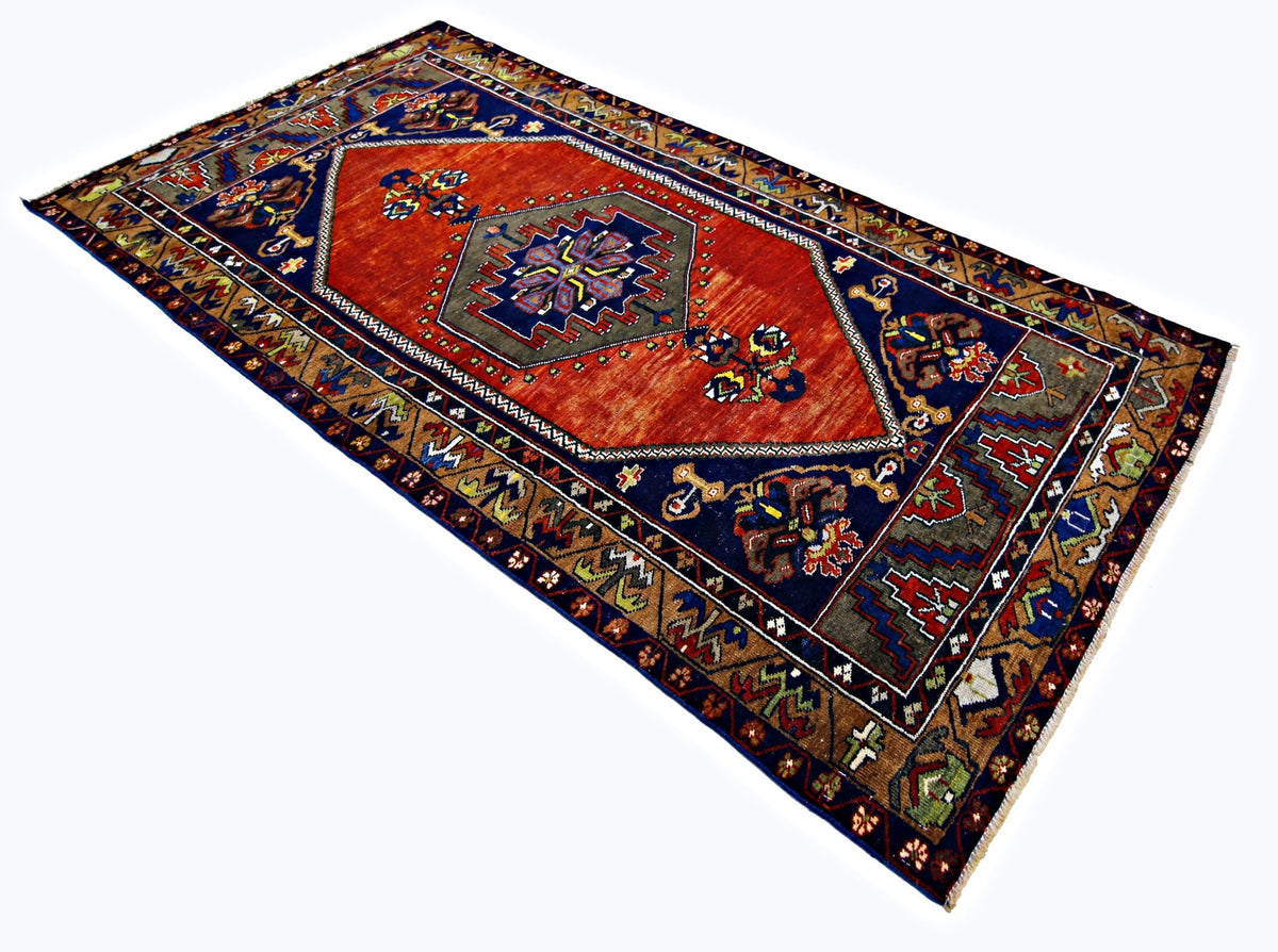 Vintage Turkish Taspinar rug with a geometric orange medallion, deep blue field, and intricate multi-coloured borders.