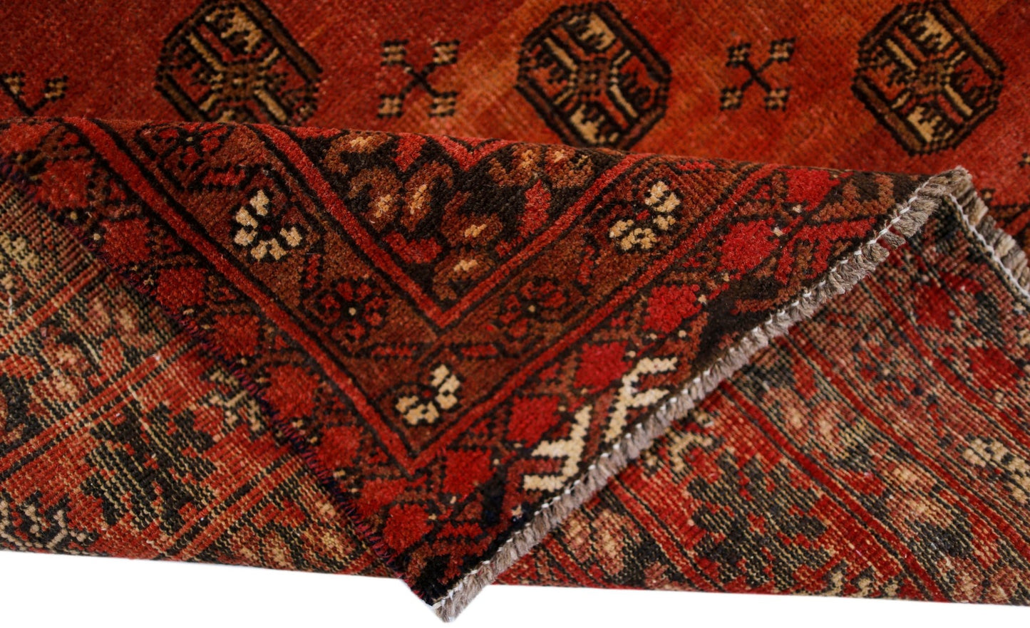 A handwoven vintage Afghan Turkmen rug featuring traditional geometric patterns in deep red and brown.