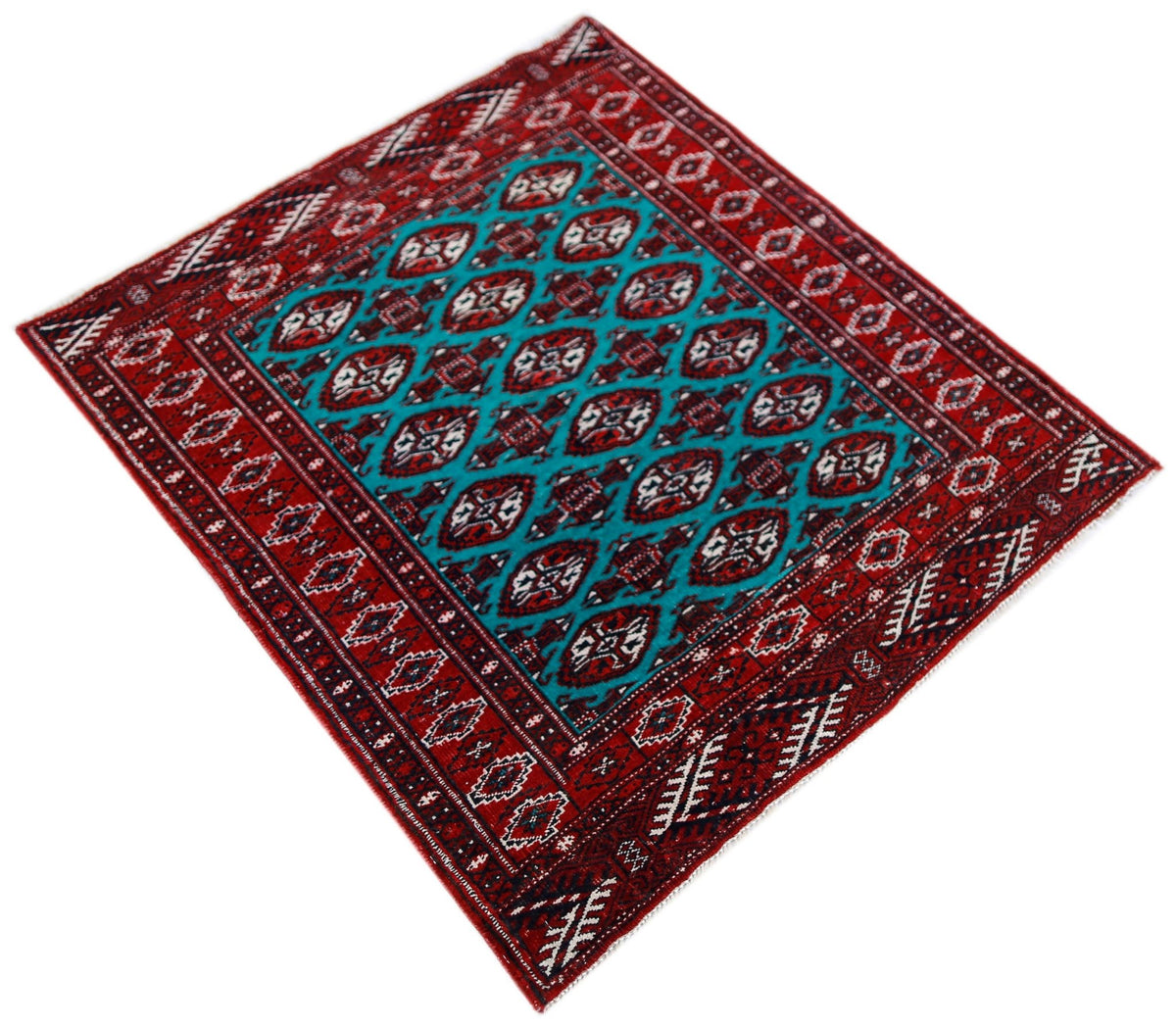Vintage Tekke rug with a deep red field, repeating octagonal gul medallions, and contrasting teal, ivory, and black accents.