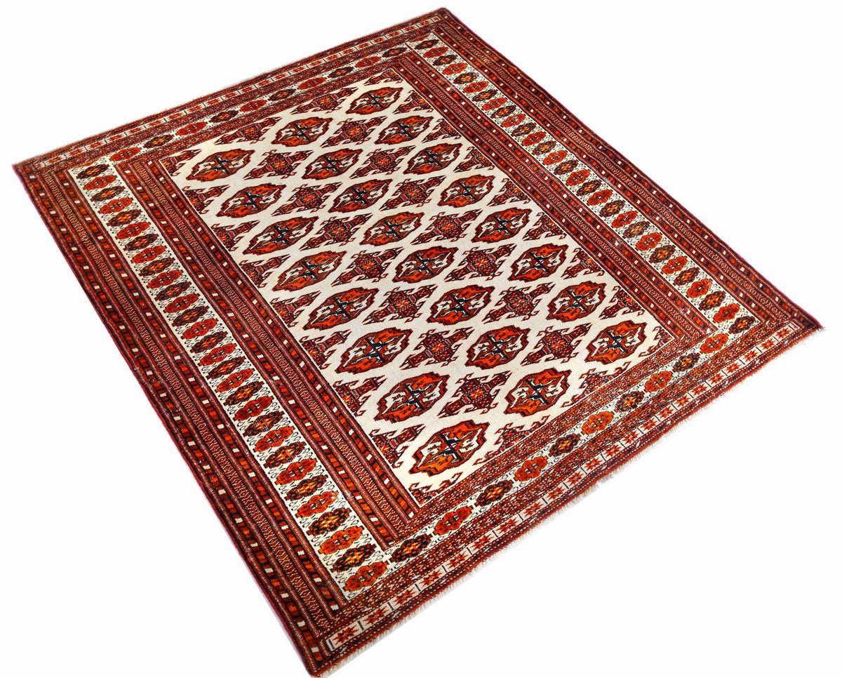 Vintage Turkmen Tekke rug featuring repeating octagonal gul medallions in crimson, indigo, and ivory on a white field.