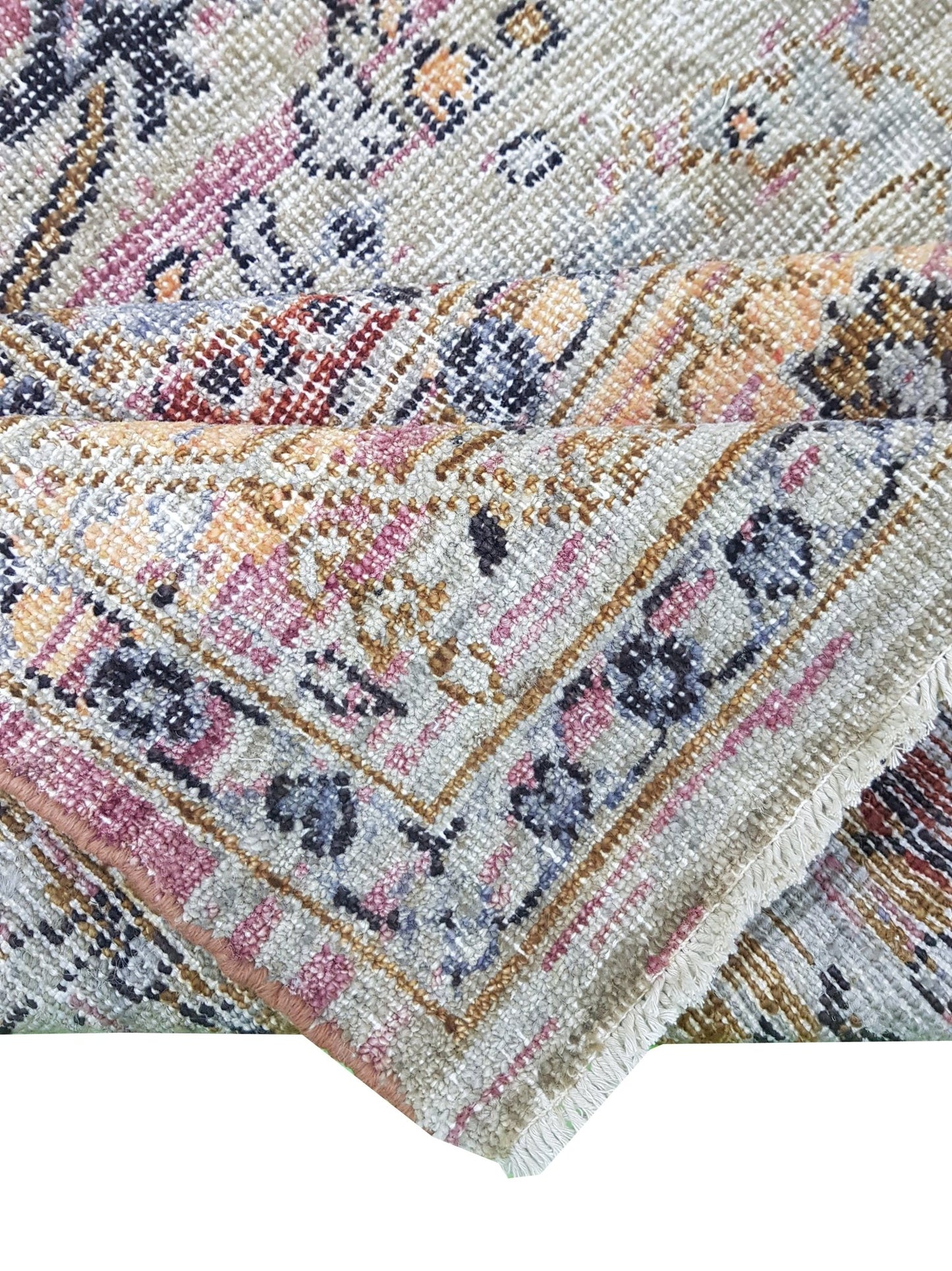 A folded transitional Oushak rug featuring a traditional pattern in muted, multi-colored tones.