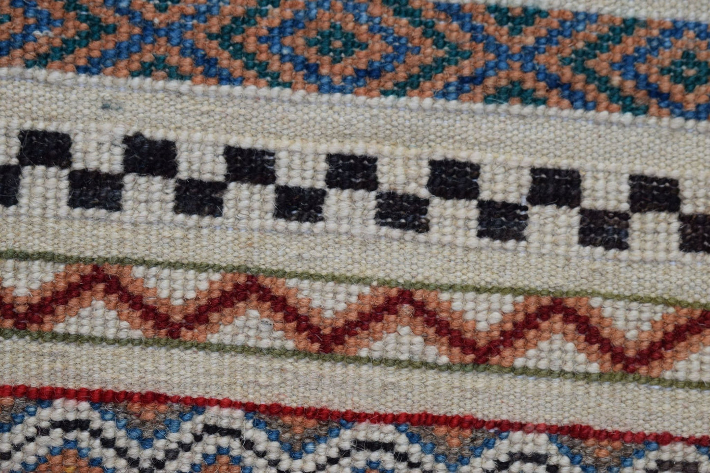 A close-up of an Afghan Yekta runner featuring geometric patterns in blue, orange, and black wool.