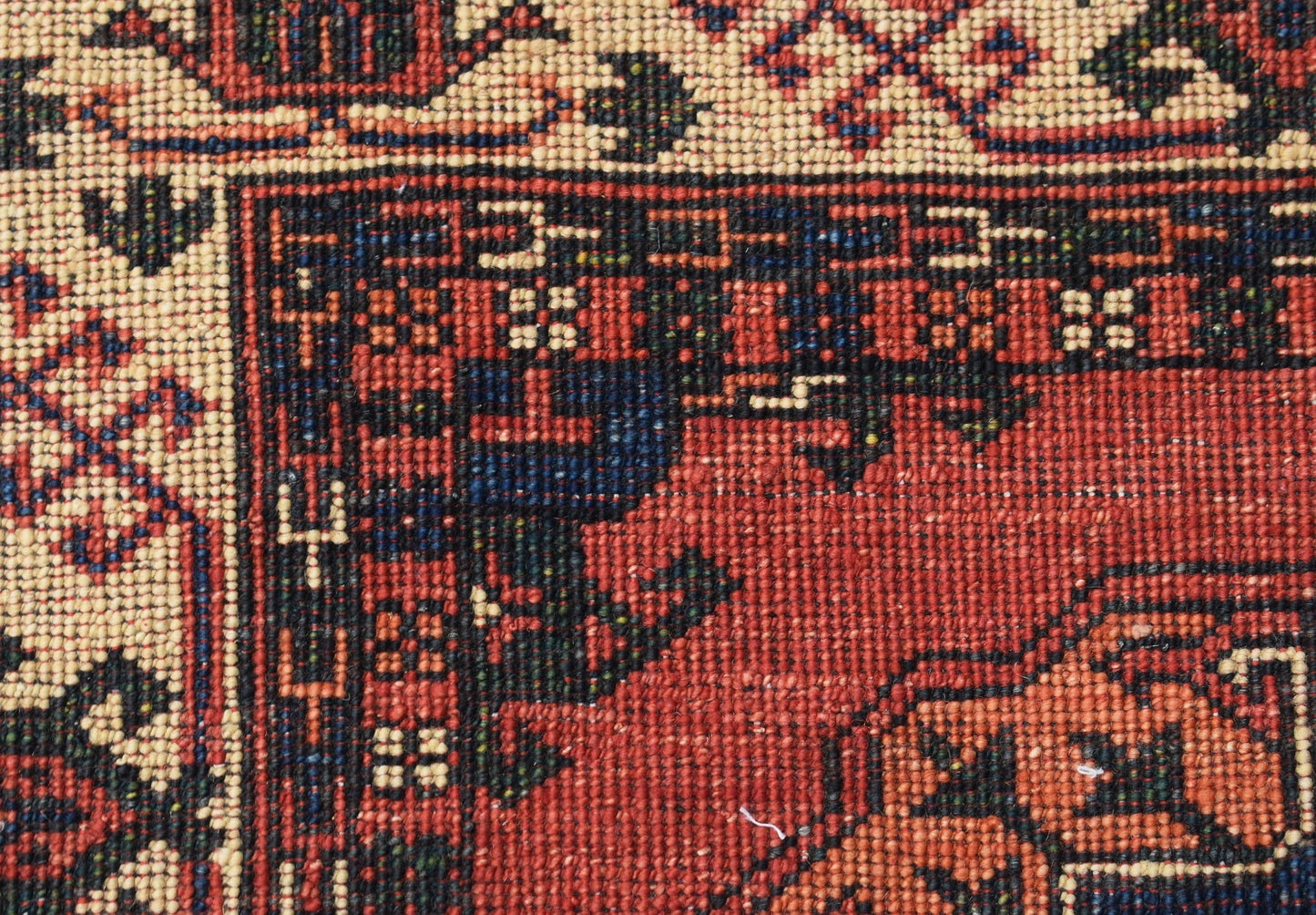 A close-up of a handwoven Afghan Chobi runner featuring intricate geometric patterns in red and blue.
