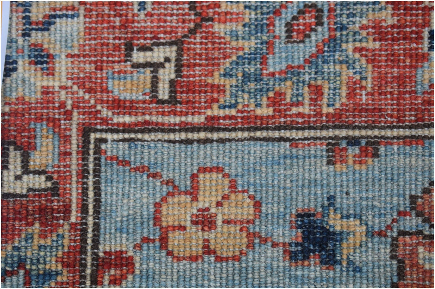 A close-up of an Afghan Chobi runner featuring traditional floral patterns in red and blue wool.