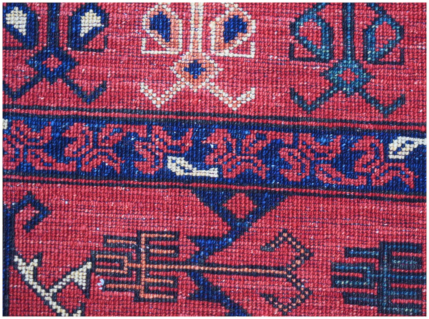 A close-up of a handwoven Afghan Chobi rug featuring traditional geometric patterns in red and blue.