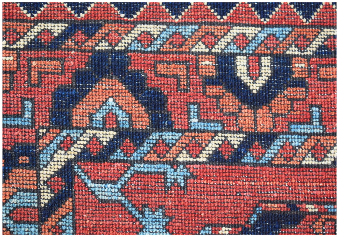 A close-up of a handwoven Afghan Chobi rug featuring intricate geometric patterns in red and blue.