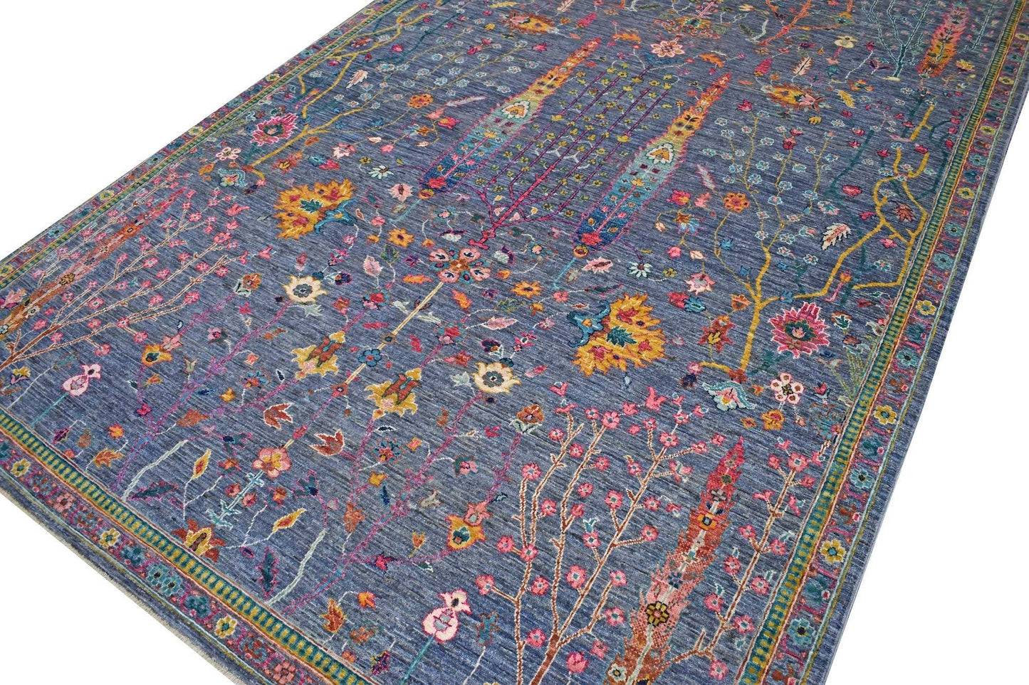 A handmade Afghan Chobi rug featuring a blue field with intricate floral and botanical patterns.