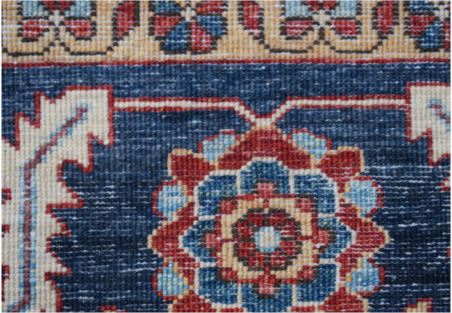 A close-up of a handmade Afghan Chobi rug featuring a floral medallion on a deep blue field.