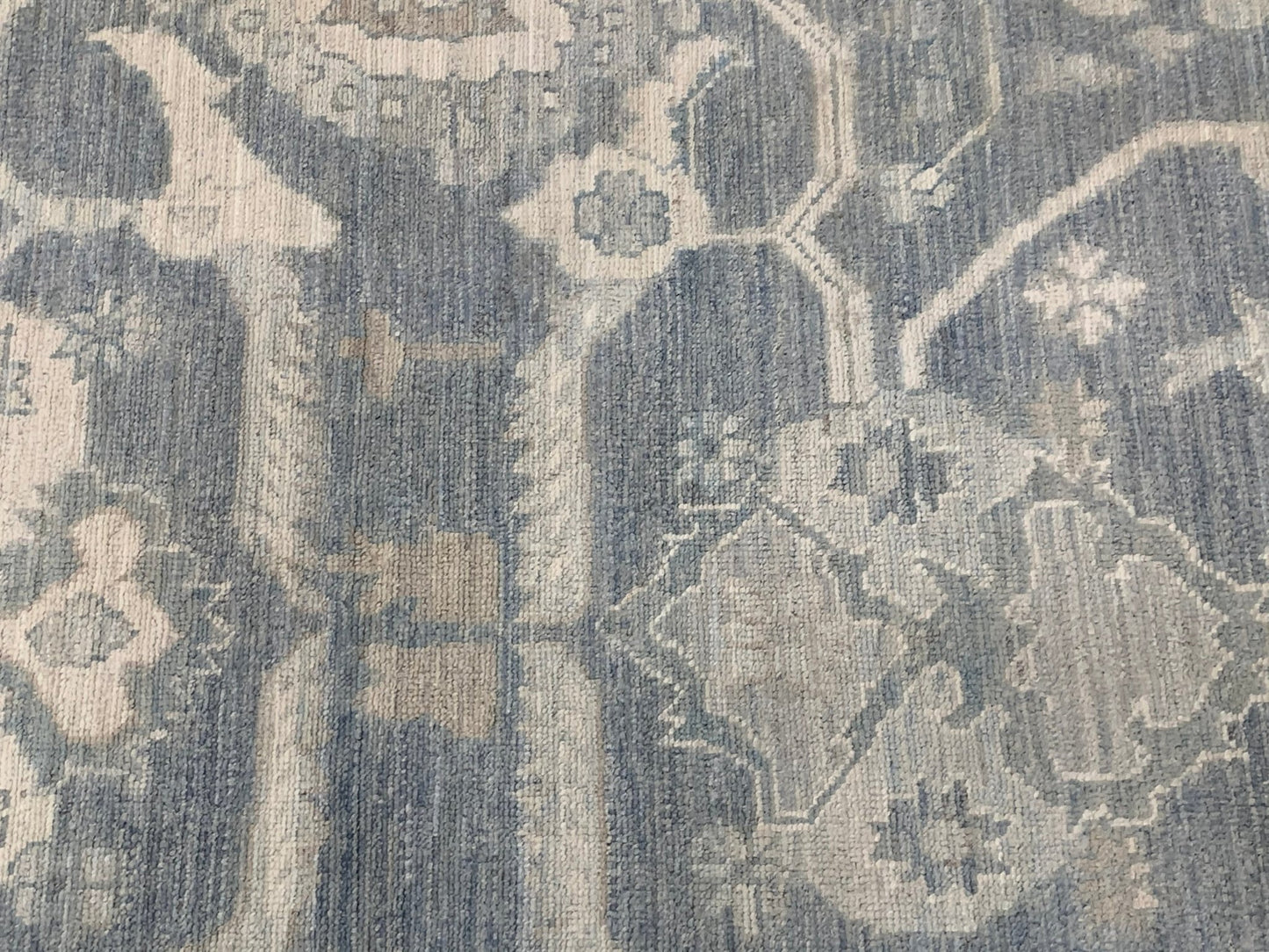A handmade Afghan Chobi rug featuring a traditional blue and cream floral pattern.
