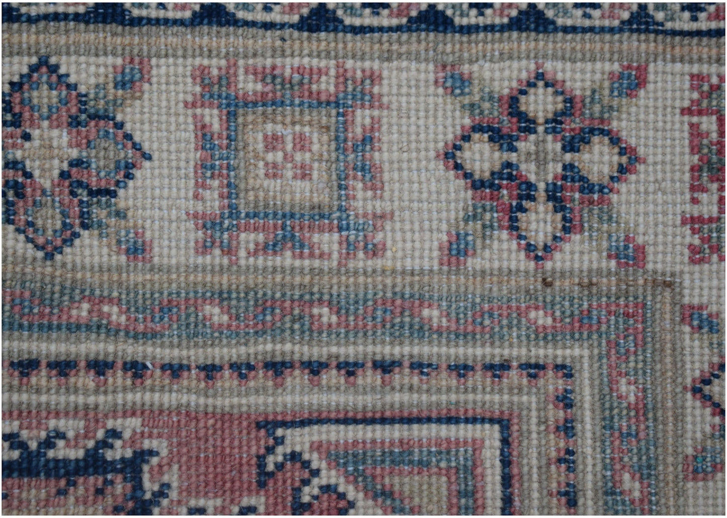 A close-up of an Afghan Kazakh runner featuring traditional geometric motifs in blue and pink.