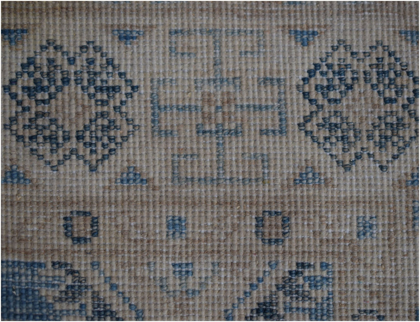 A handmade Afghan Kazakh runner featuring a beige wool base with intricate blue geometric patterns.