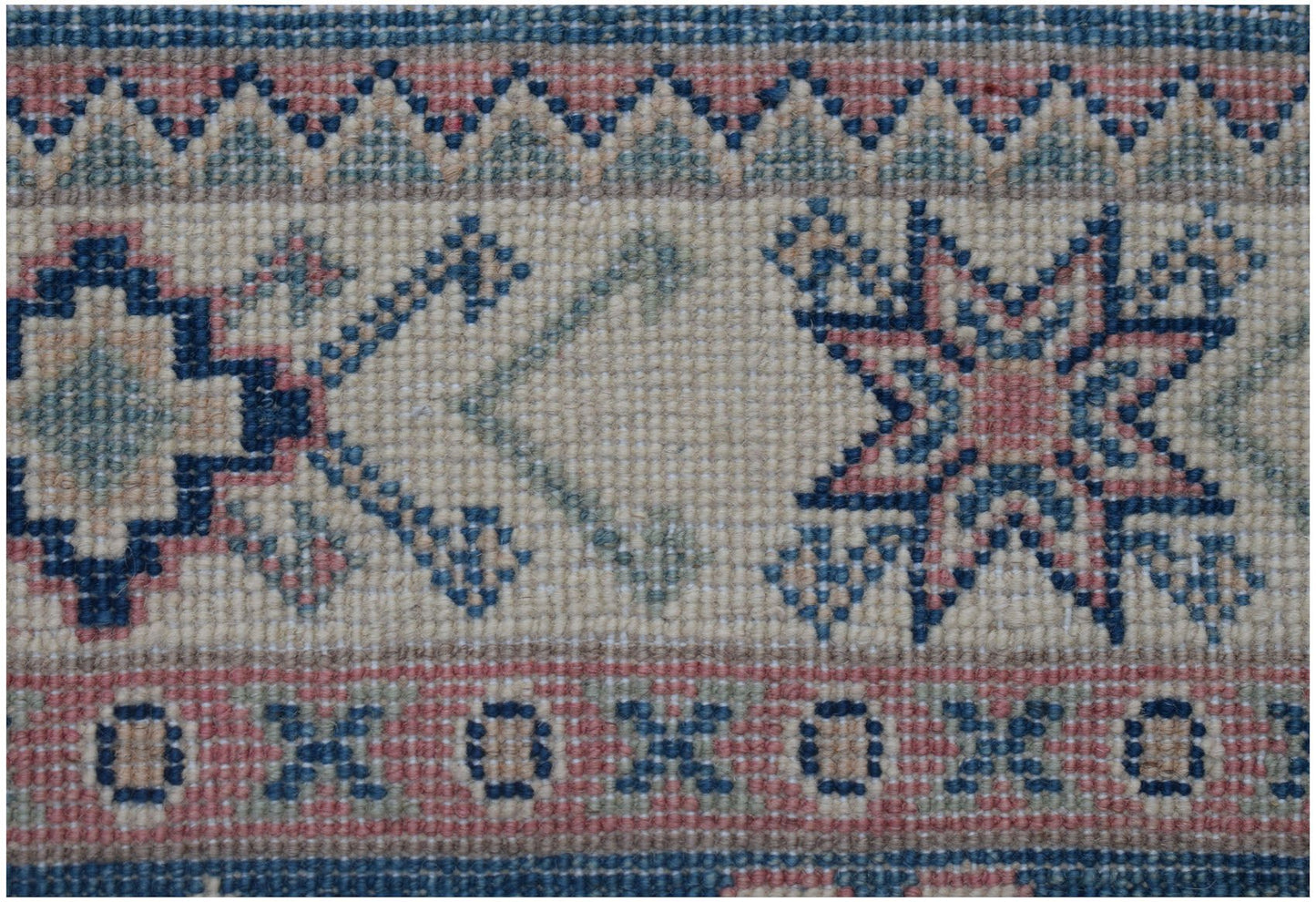 A close-up of an Afghan Kazakh runner featuring traditional geometric star and border motifs.