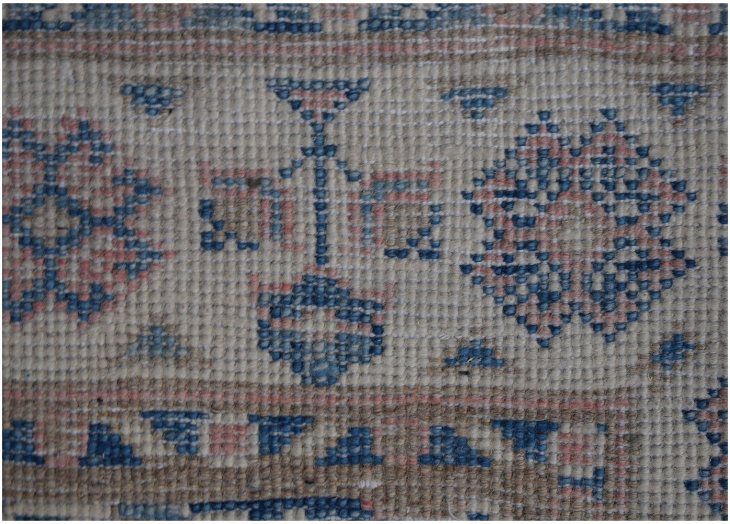 A close-up of an Afghan Kazakh runner rug featuring geometric floral patterns in blue and pink.