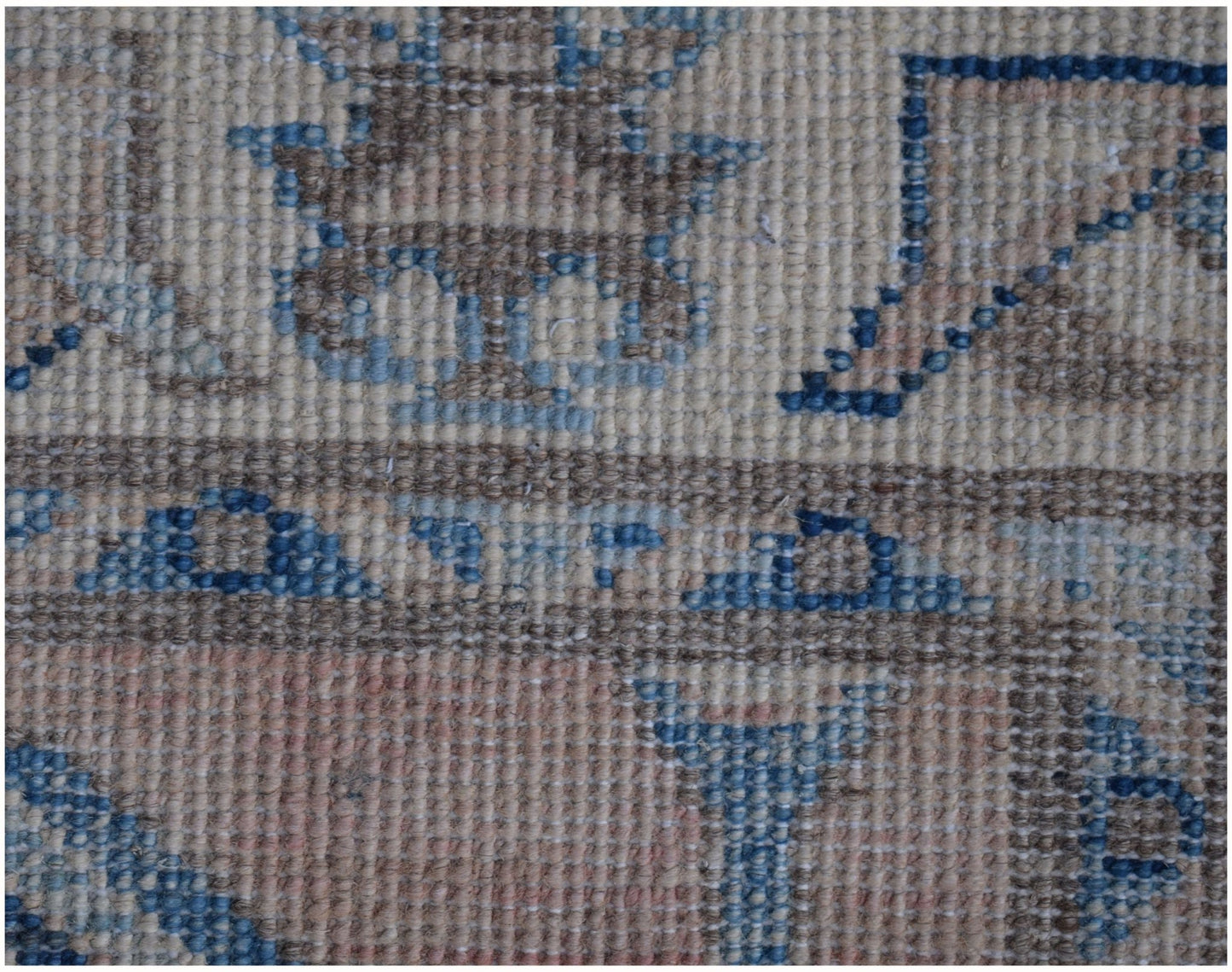 A close-up of an Afghan Kazakh runner rug featuring a geometric pattern in beige, blue, and grey.