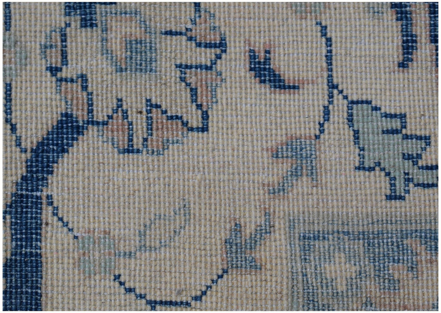 A close-up of a handmade Afghan Kazakh rug featuring traditional floral patterns in blue and beige.