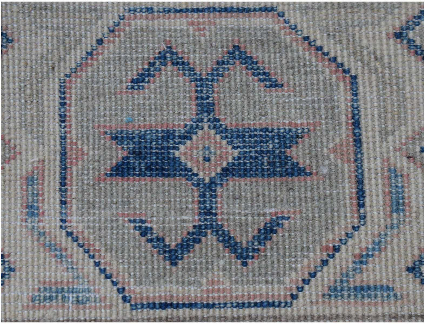 A handmade Afghan Kazakh rug featuring a central blue geometric motif on a light textured background.
