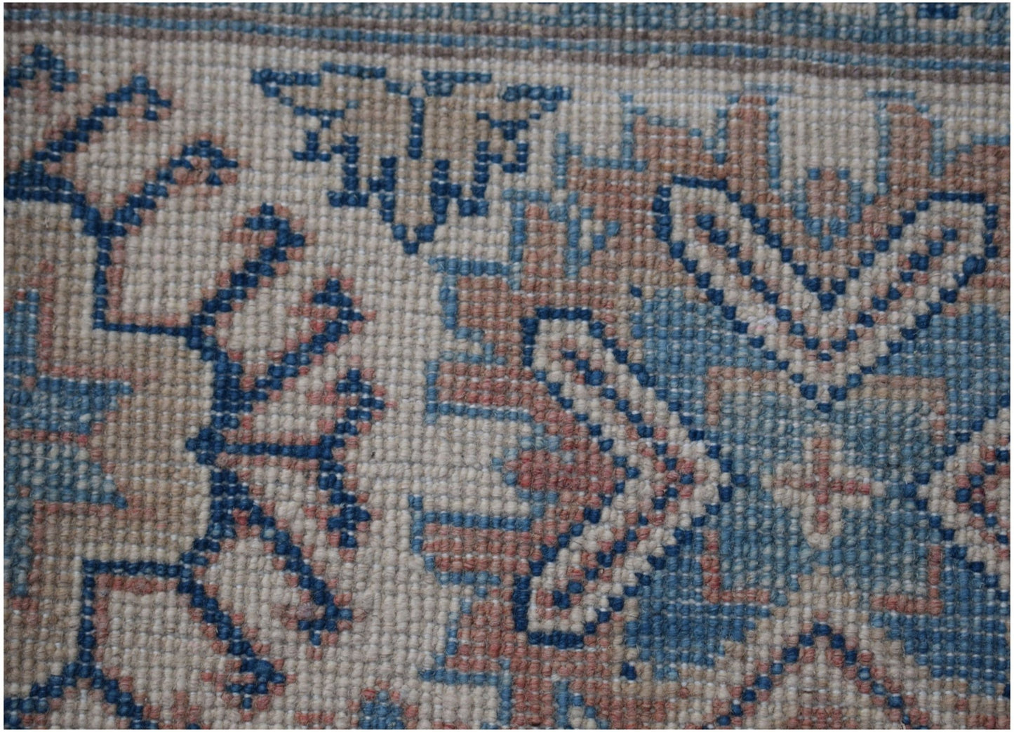A close-up of an Afghan Kazakh rug featuring traditional geometric patterns in blue and tan wool.