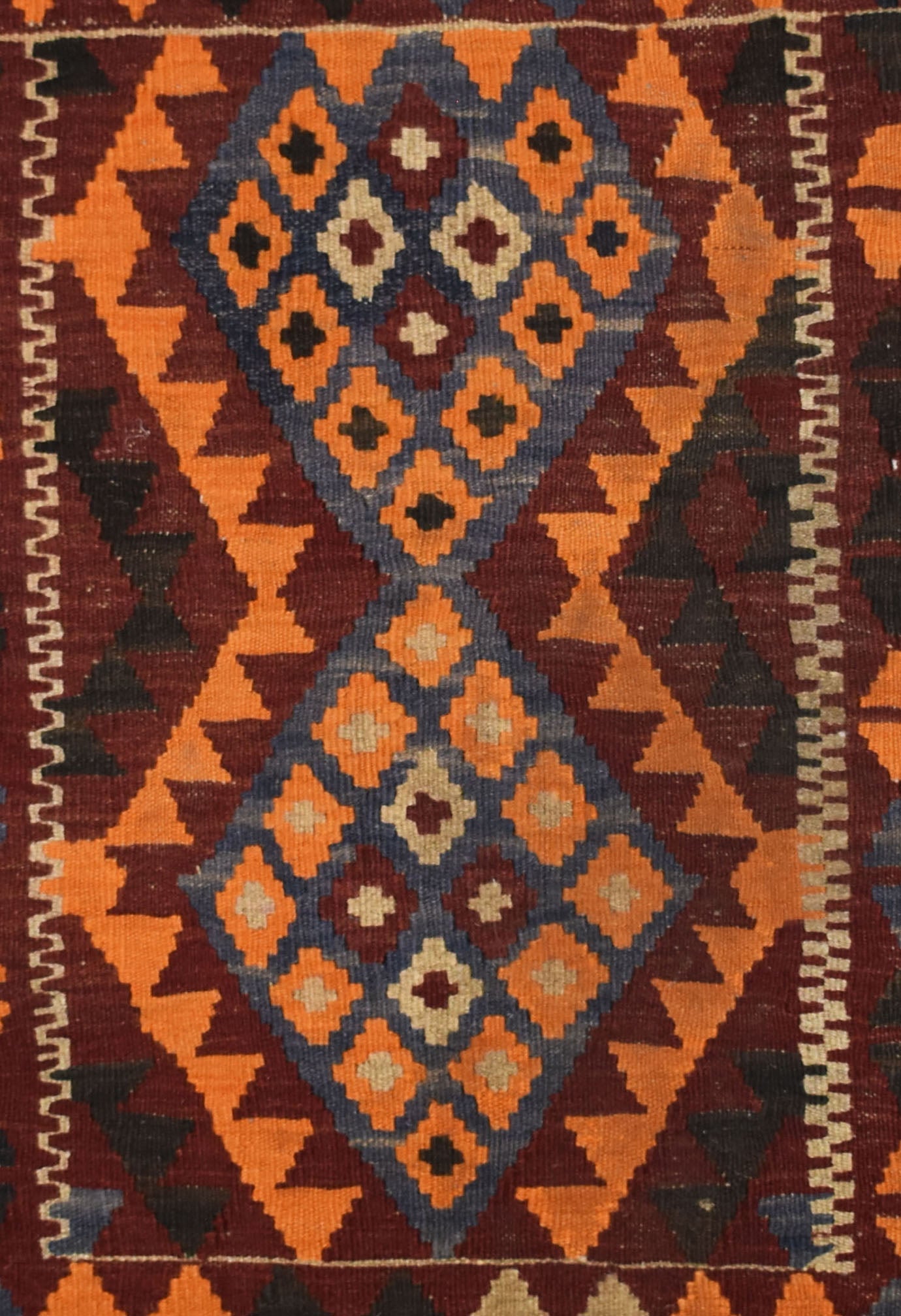 Handmade Afghan Maimana kilim rug featuring a geometric diamond pattern in orange, blue, and brown.