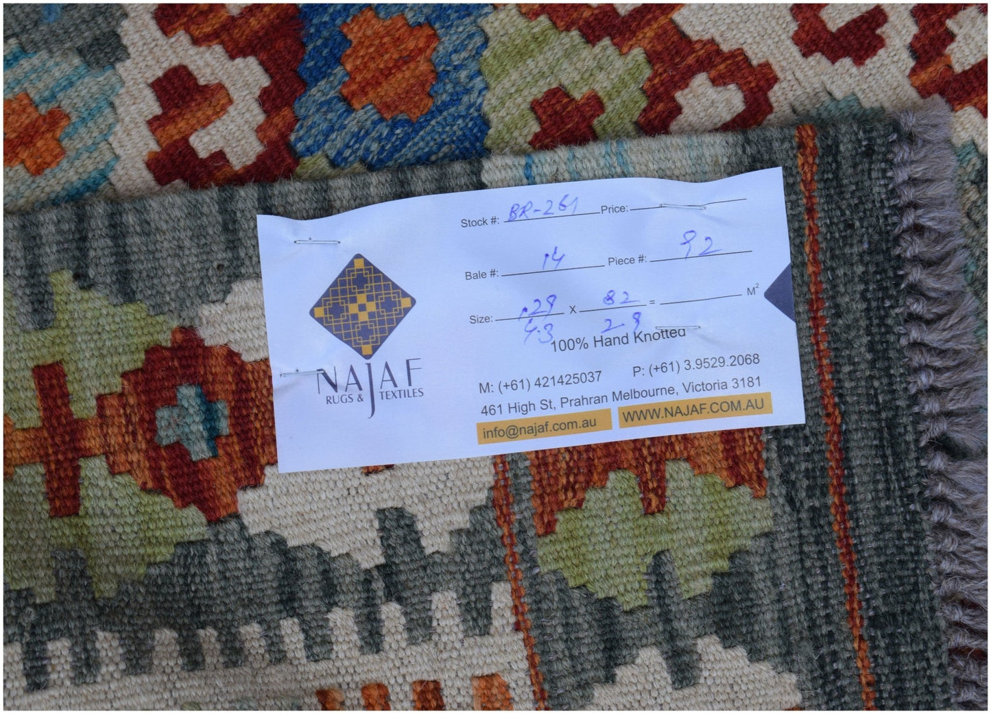 A handmade Afghan Maimana kilim rug featuring a geometric pattern in blue, orange, and green.