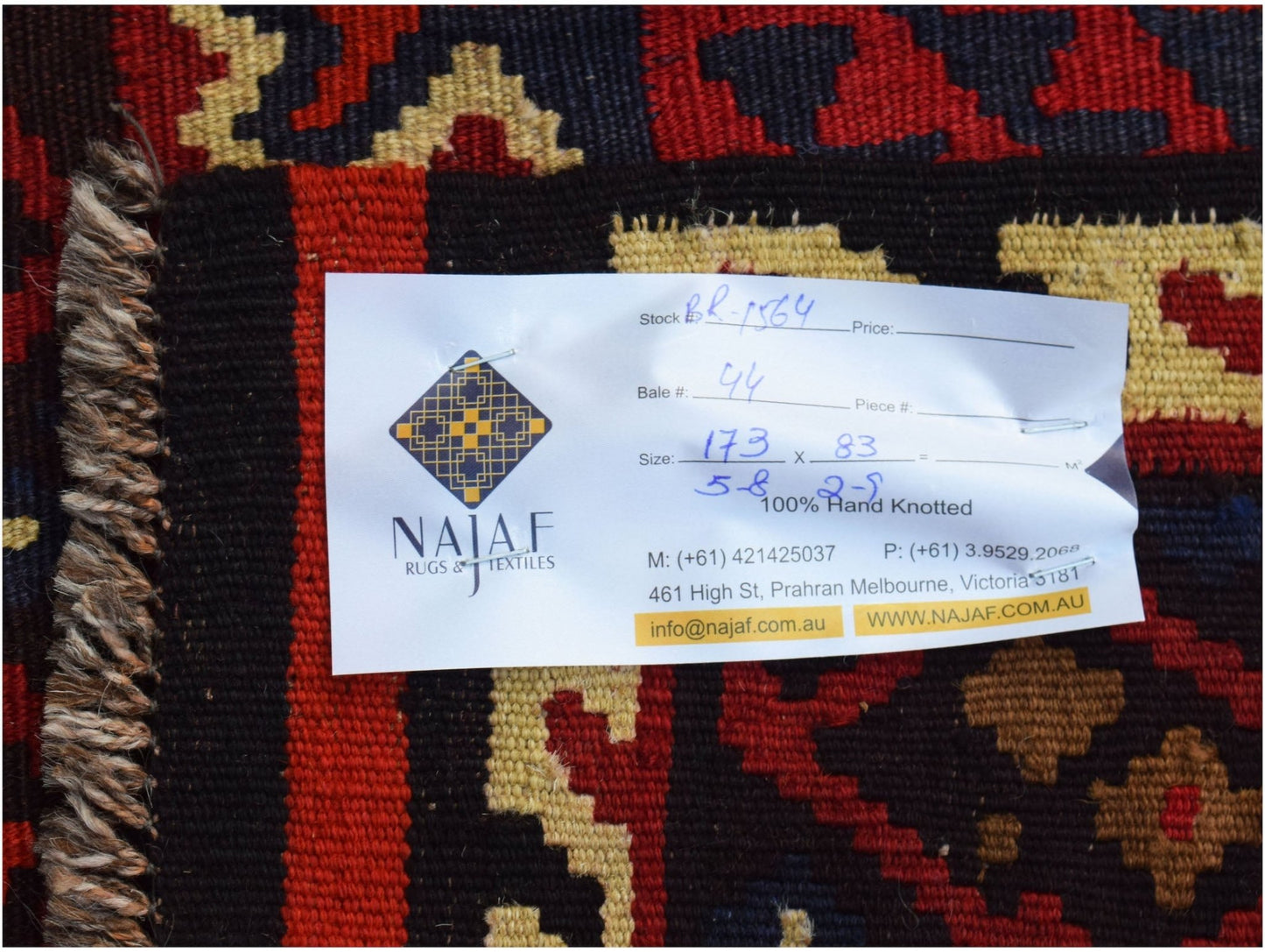 A handwoven Afghan Maimana kilim featuring a geometric pattern in red, black, and tan wool.