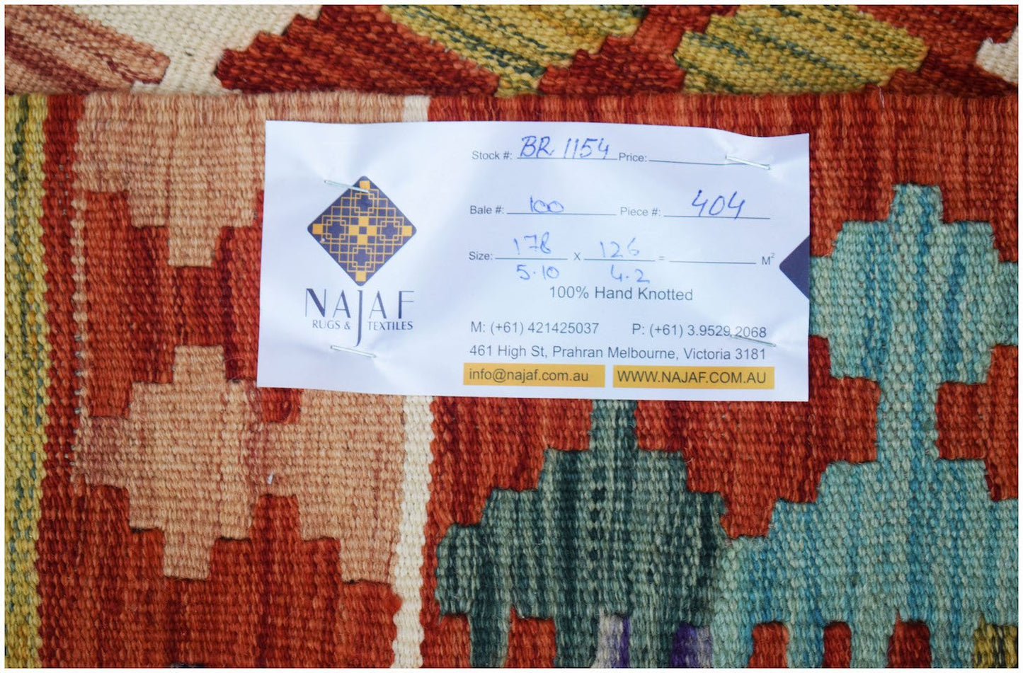 A handwoven Afghan Maimana kilim featuring a vibrant geometric pattern in red, blue, and yellow.