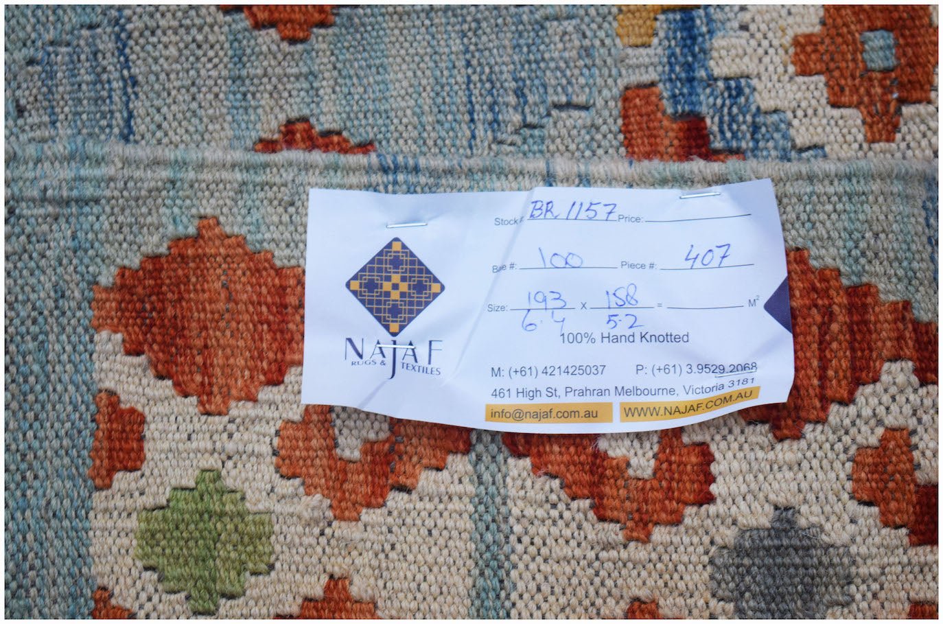 A handwoven Afghan Maimana kilim featuring a geometric pattern in orange, green, and blue tones.